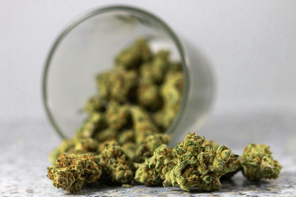 Detailed image of cannabis buds spilling from a glass jar, highlighting the green texture.